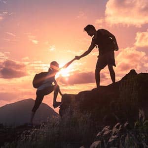 A person helping another up a hill.