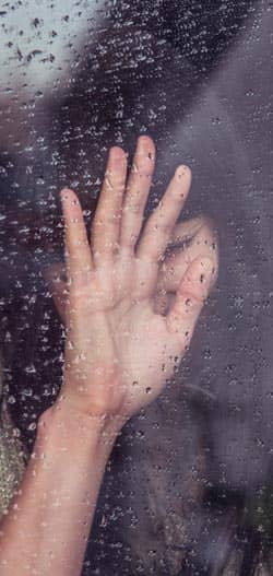 Addiction is a prison. A woman in a window on a rainy day