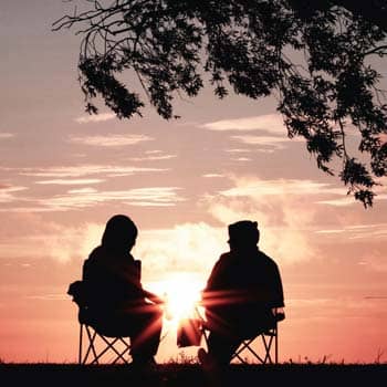 Two people sitting and talking in the sunset