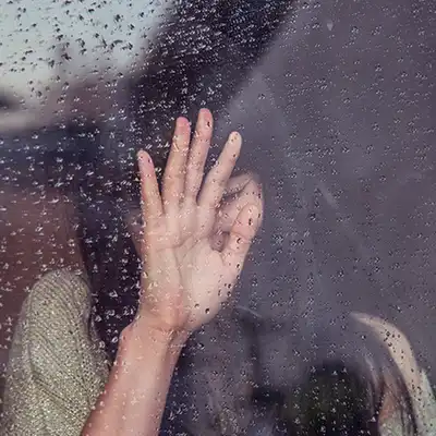 Woman leaning on window on a rainny day